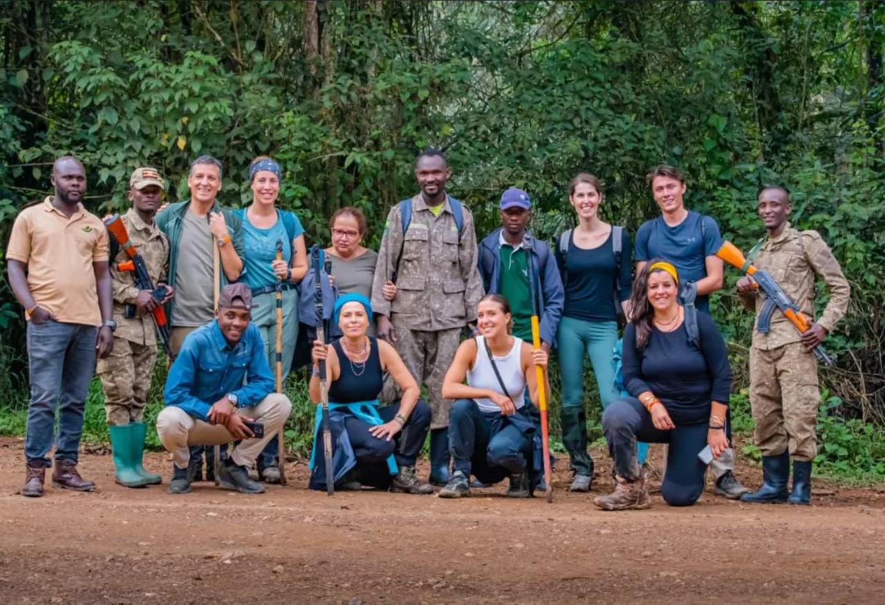 Two trekkers descend a forest path with a ranger after a gorilla morning