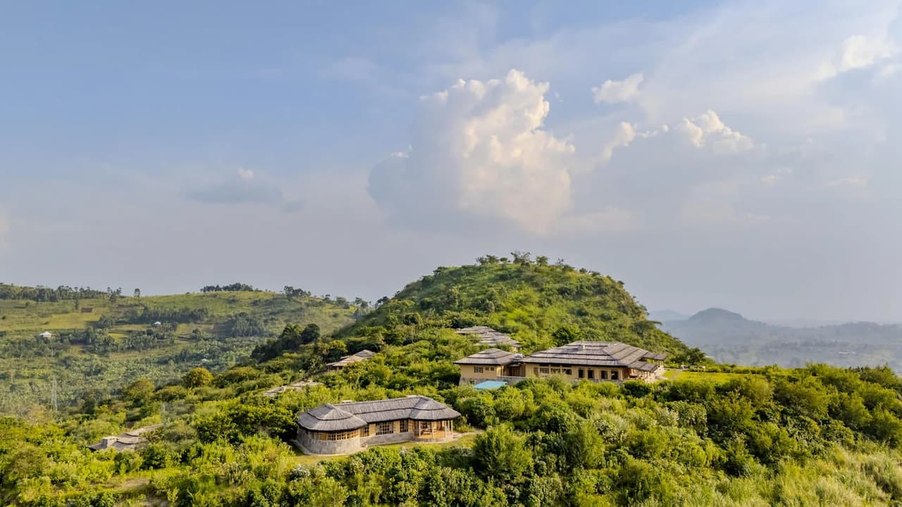 A forest lodge sits amid green hills at the edge of Kibale