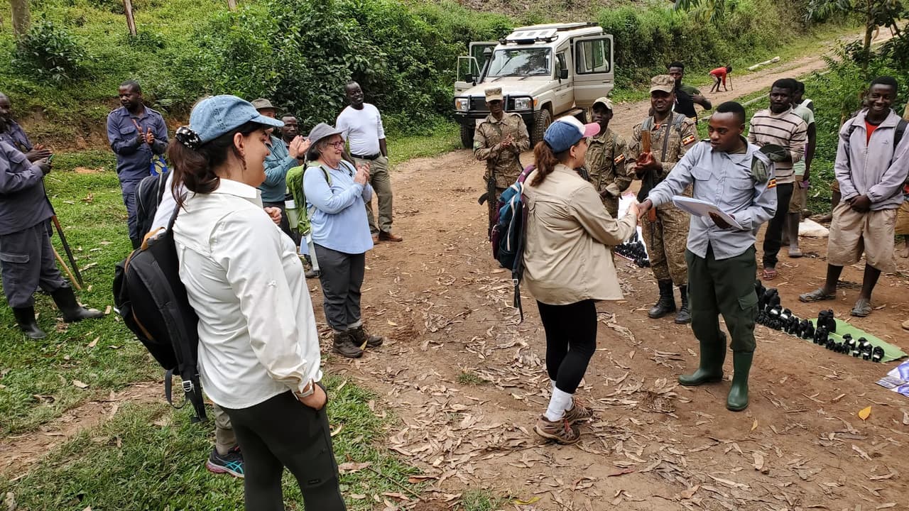 Porters and rangers with bags gather at a Bwindi trailhead, preparing for a gorilla trek
