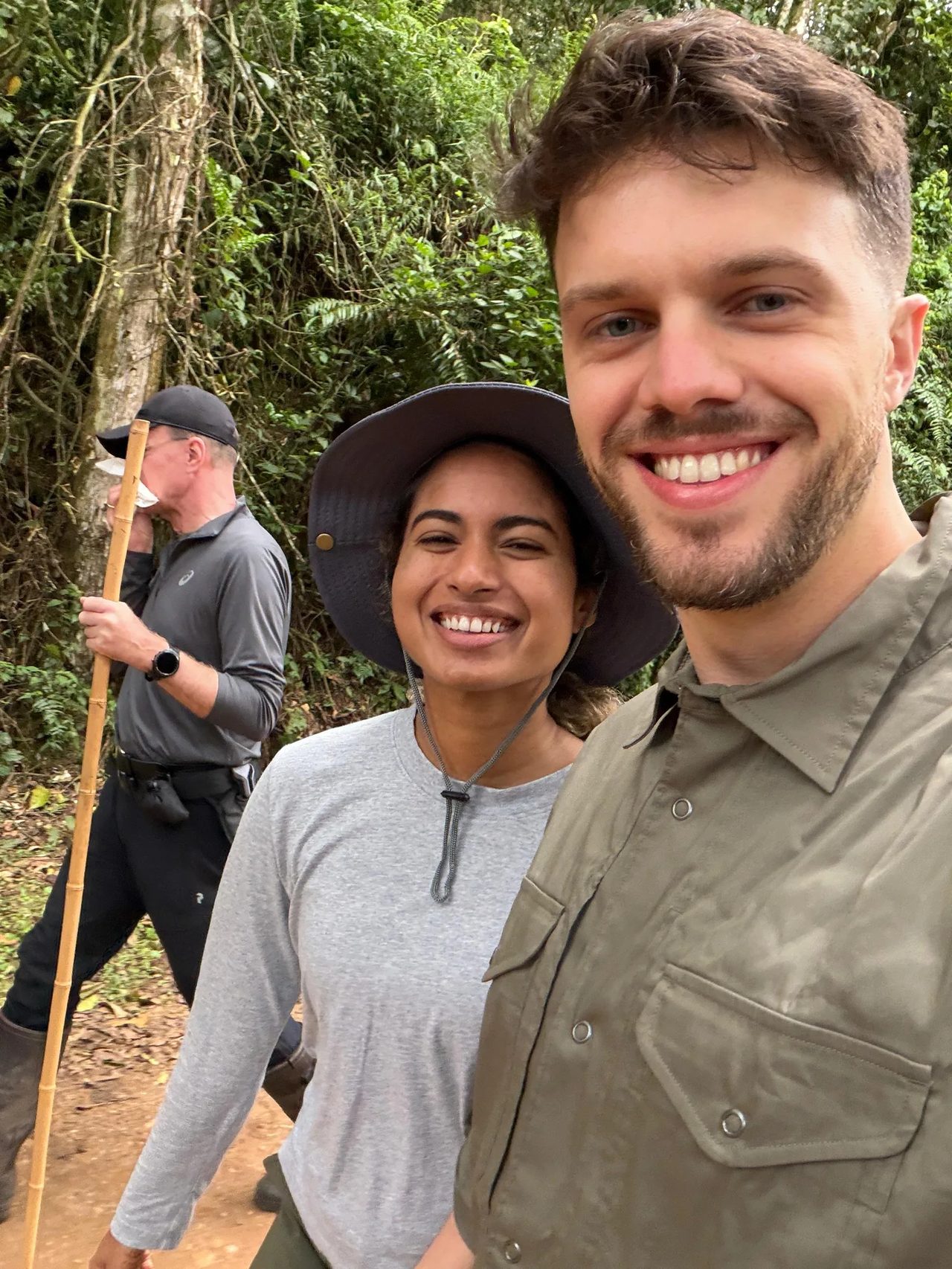 A couple smile on the forest trail after their gorilla trek