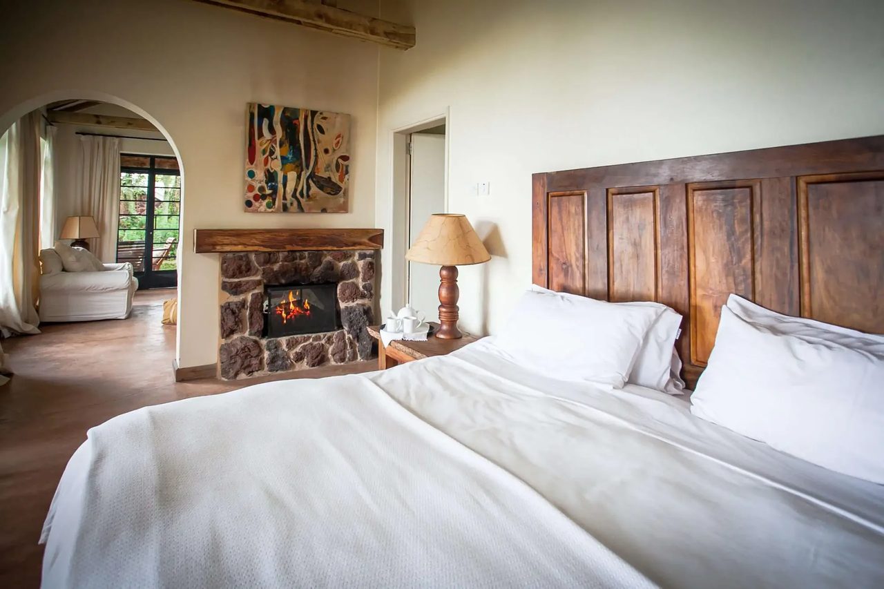 A double bedroom at Clouds Mountain Gorilla Lodge, timber furniture and a forest-facing window