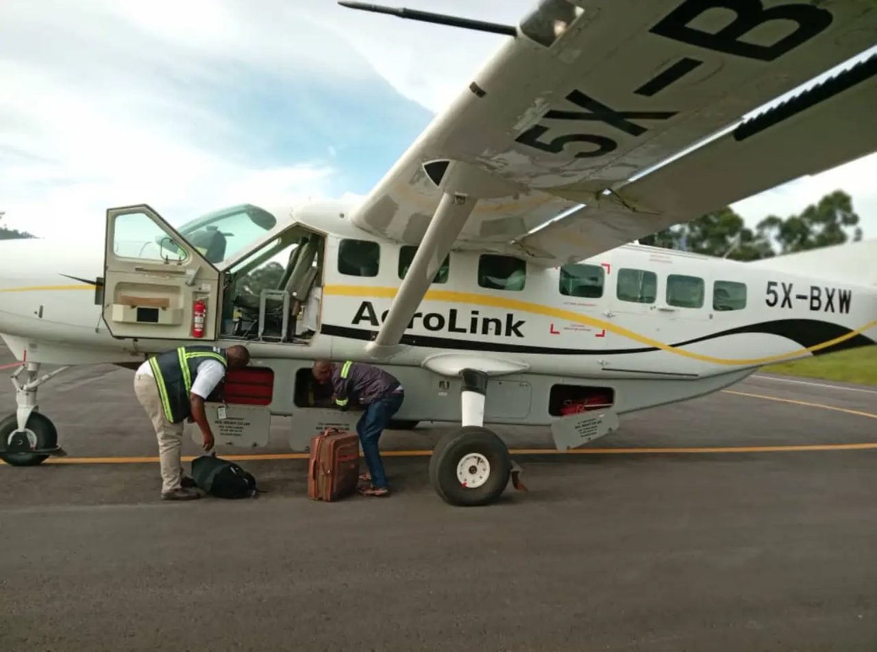 Soft-sided luggage being loaded into a small Aerolink aircraft in Uganda