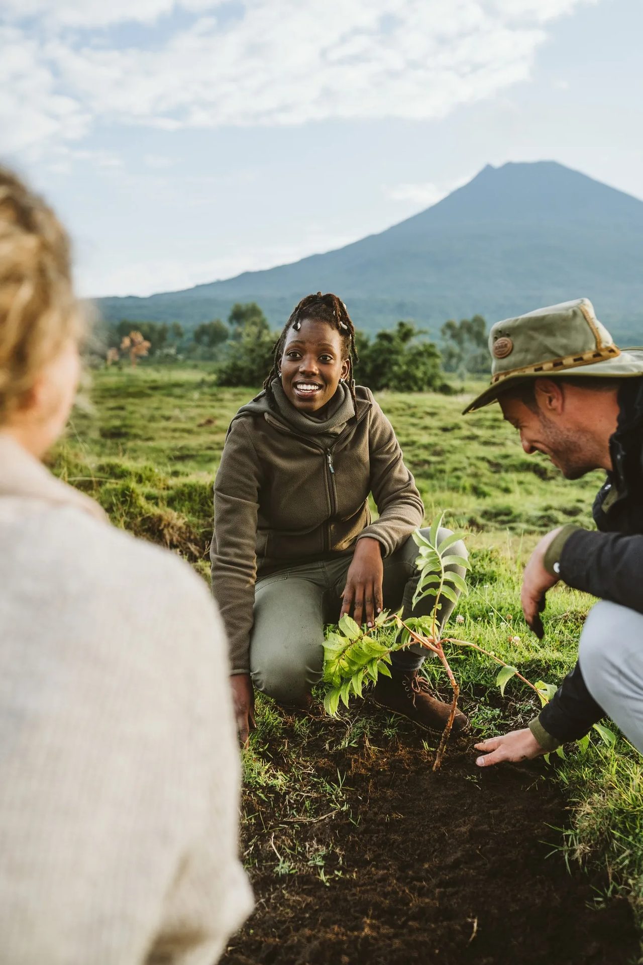 Children and guides plant seedlings beneath a volcano