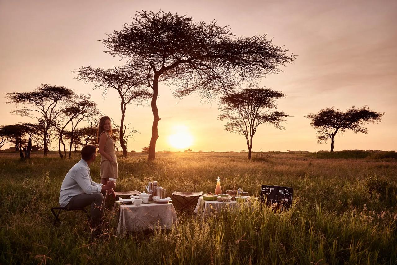 A couple sharing a private breakfast on the Tanzanian plains at sunrise