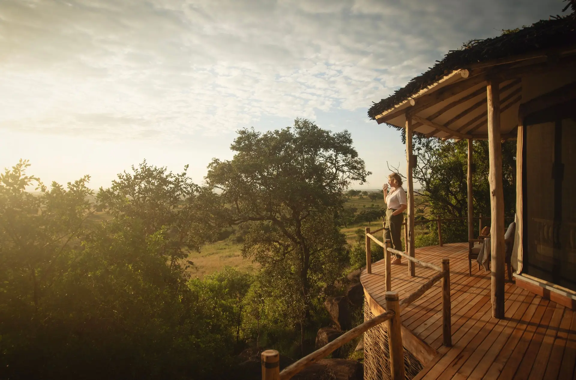 A safari guest taking in the Serengeti landscape over morning coffee
