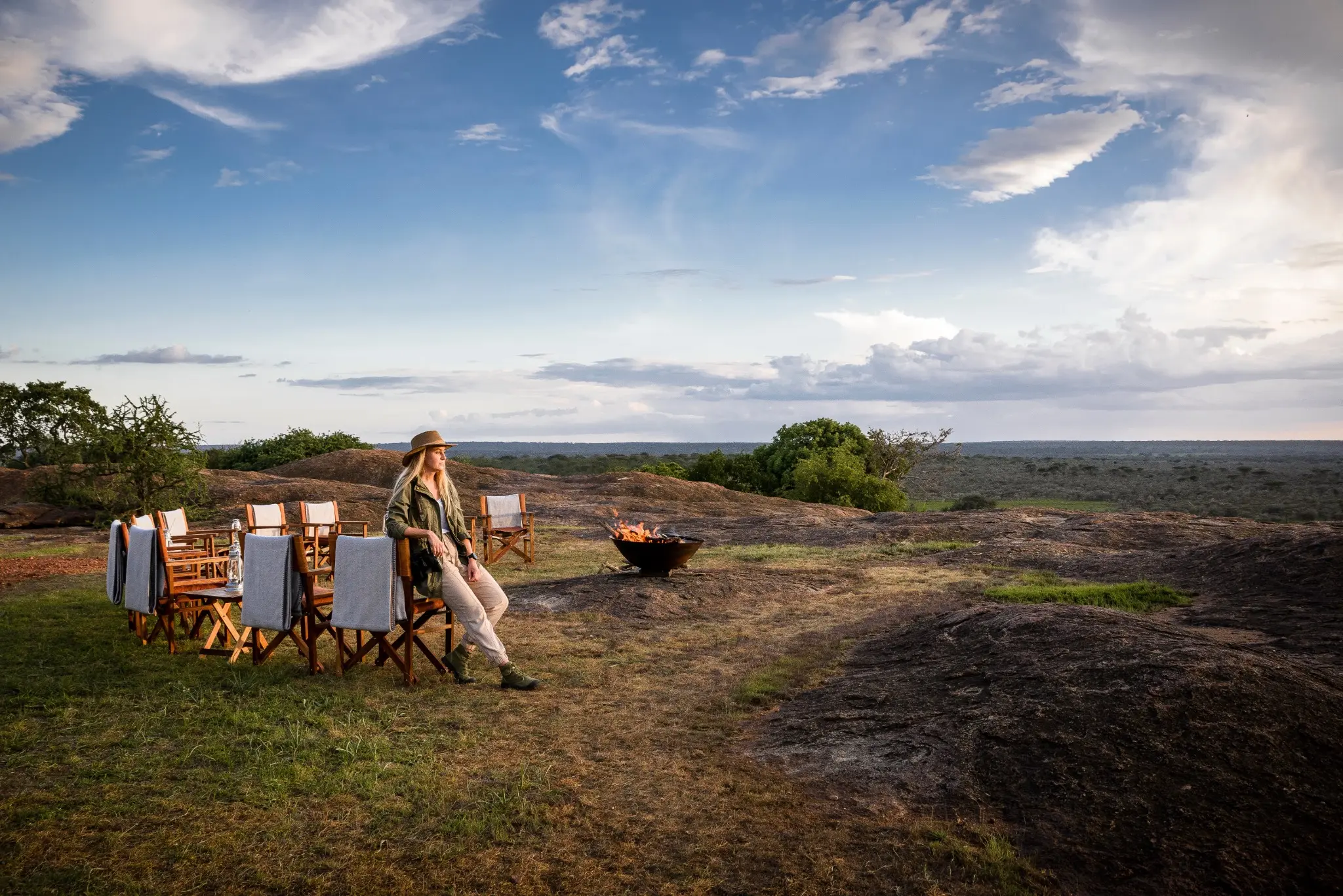 A safari guest beside a private fireside setting in a wide conservancy landscape