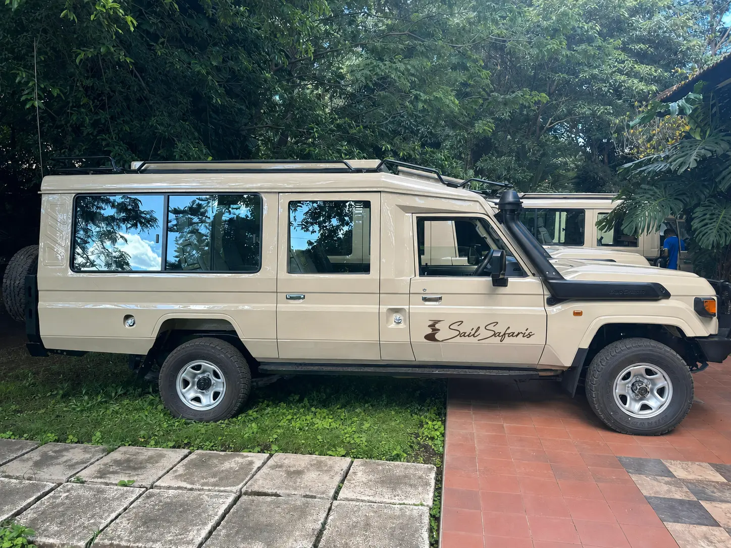 A closed, pop-up-roof Sail Safaris vehicle carrying the house wordmark