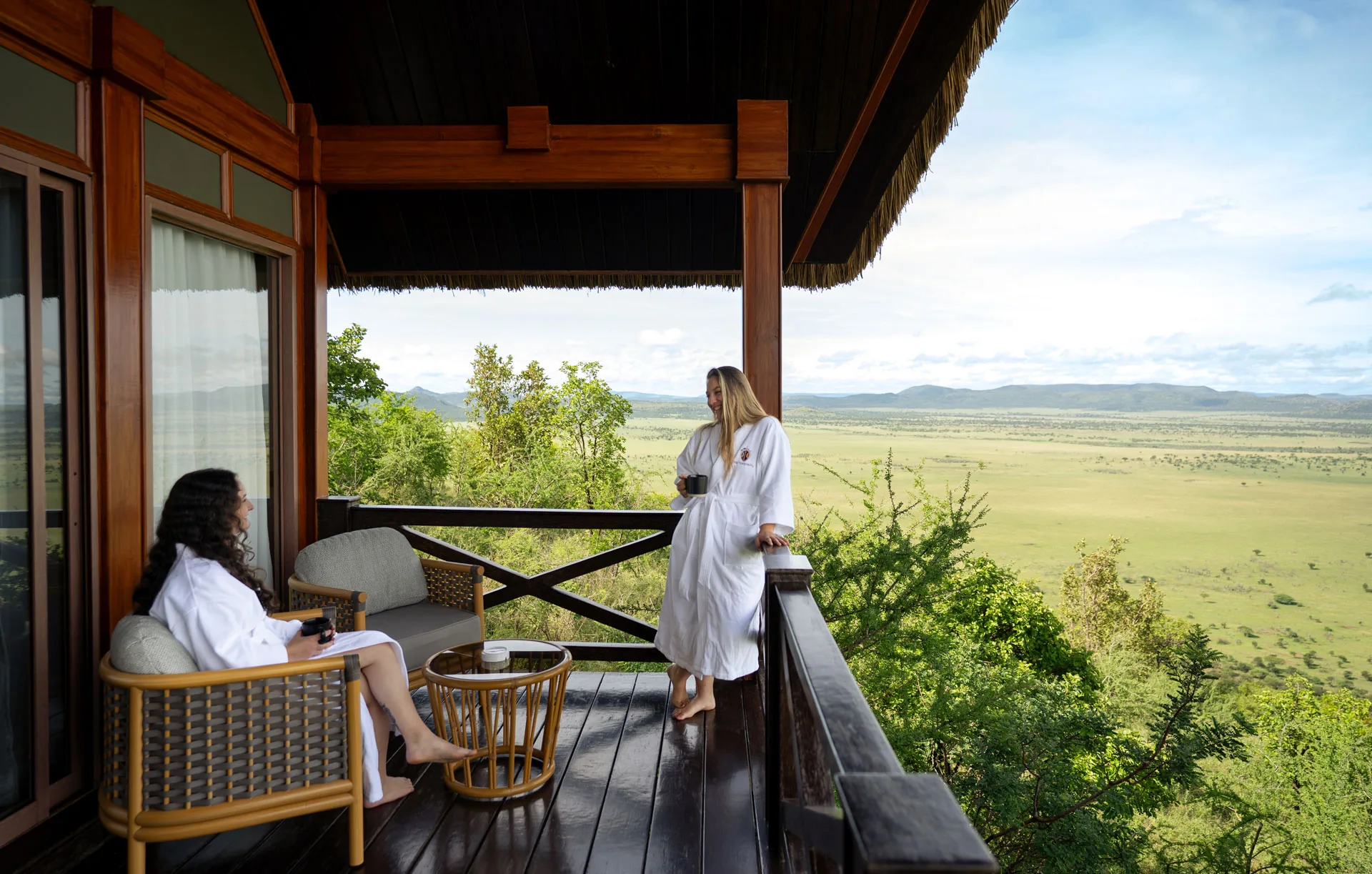 Lodge hosts attend a guest on a forest-lodge balcony