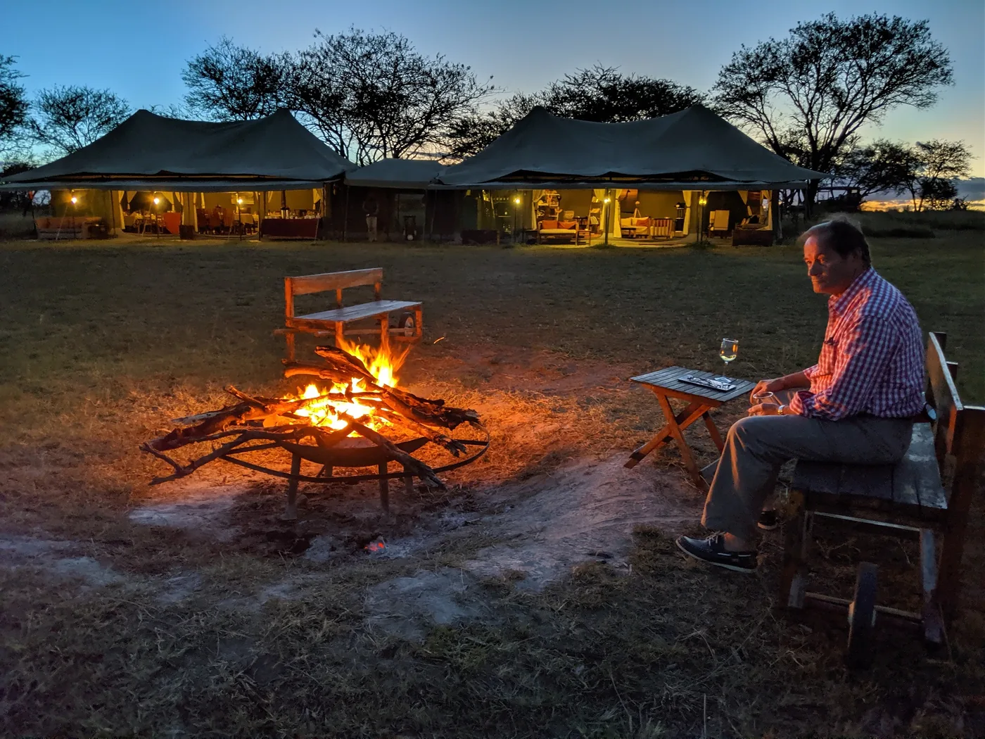 A guest rests by the campfire as evening settles over camp