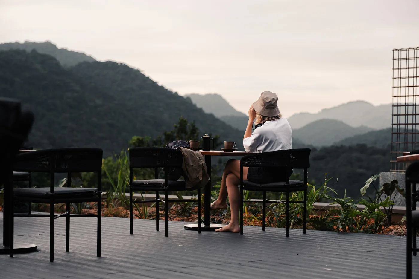 A guest looks out from a lodge deck over the forest hills