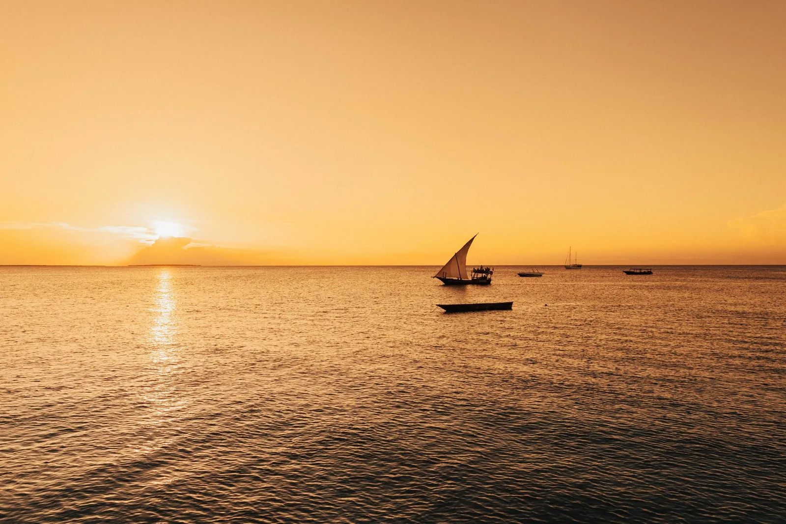 A dhow crosses the golden water at dusk