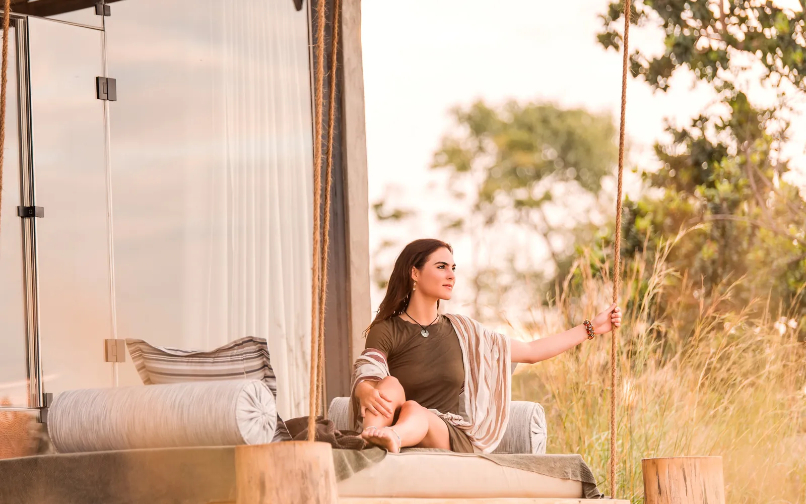 A guest rests on a daybed at the open edge of her tent
