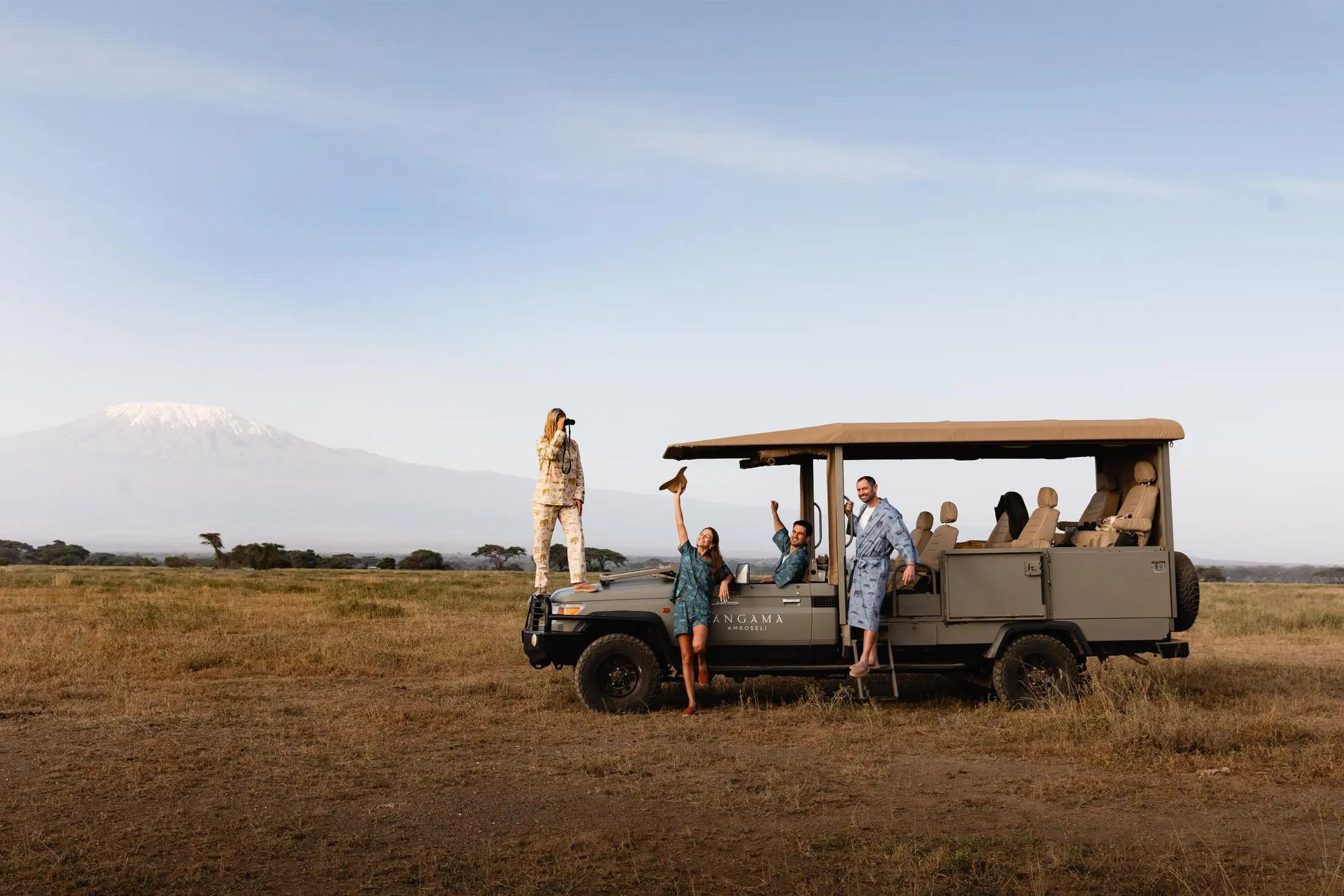 Guests beside a safari vehicle with Mount Kilimanjaro on the horizon in Kenya