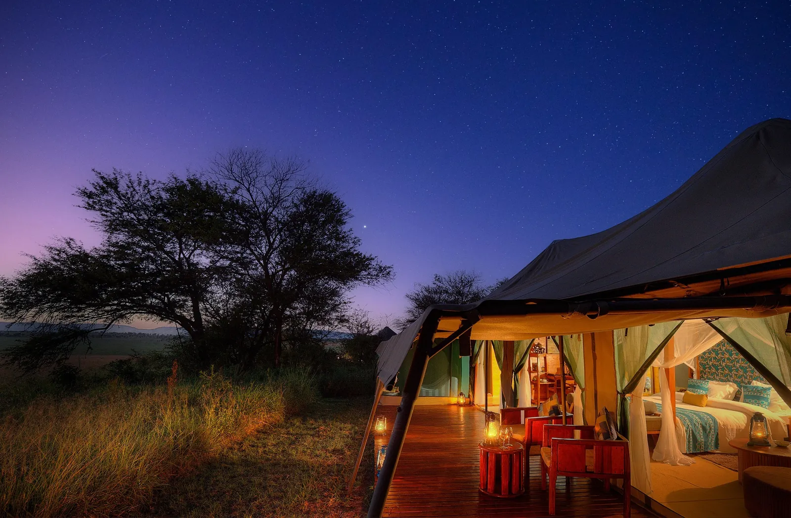 A tented suite glows at twilight under a Mara sky