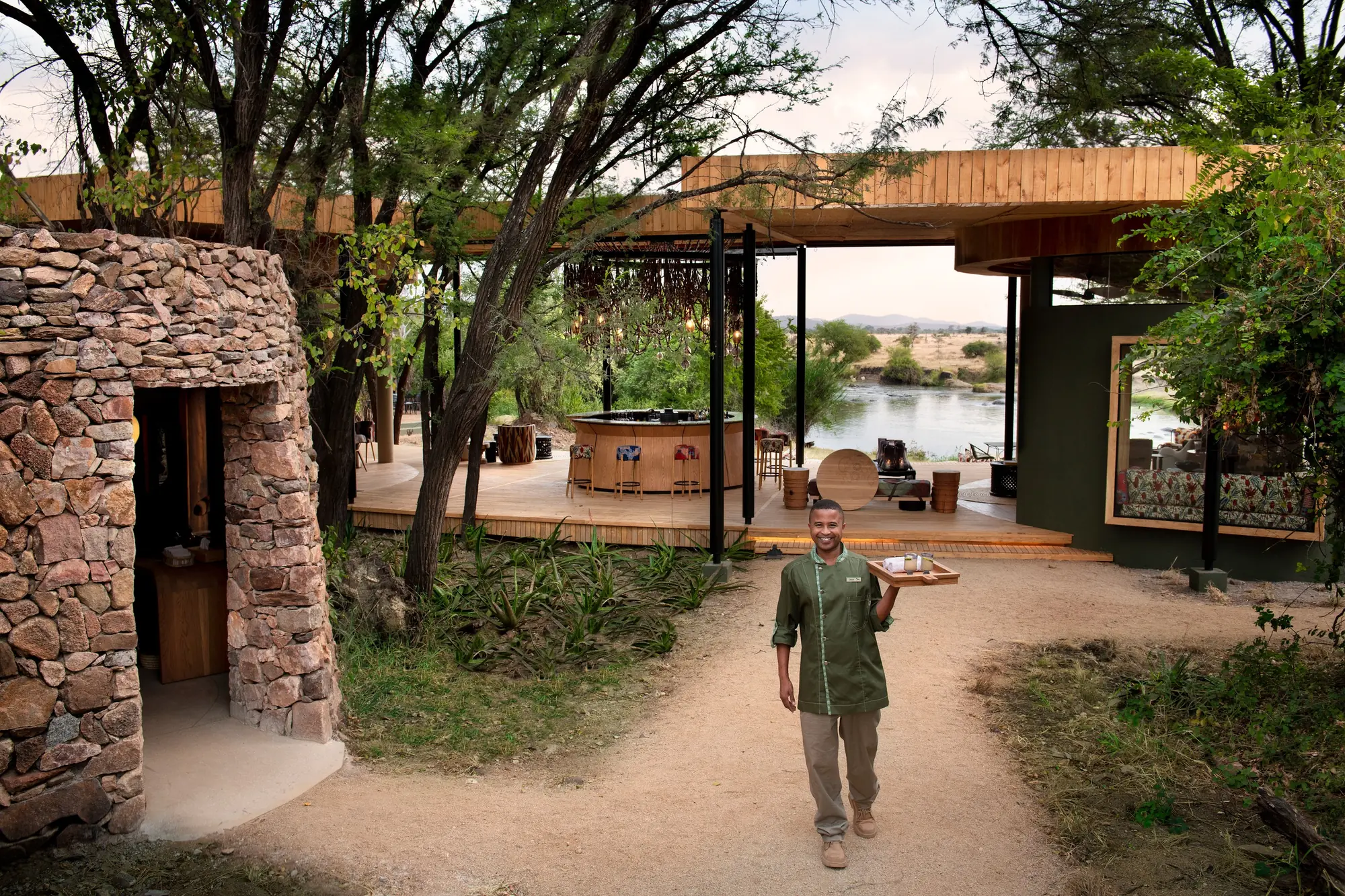 A guest is welcomed up the stone entrance path of a safari lodge