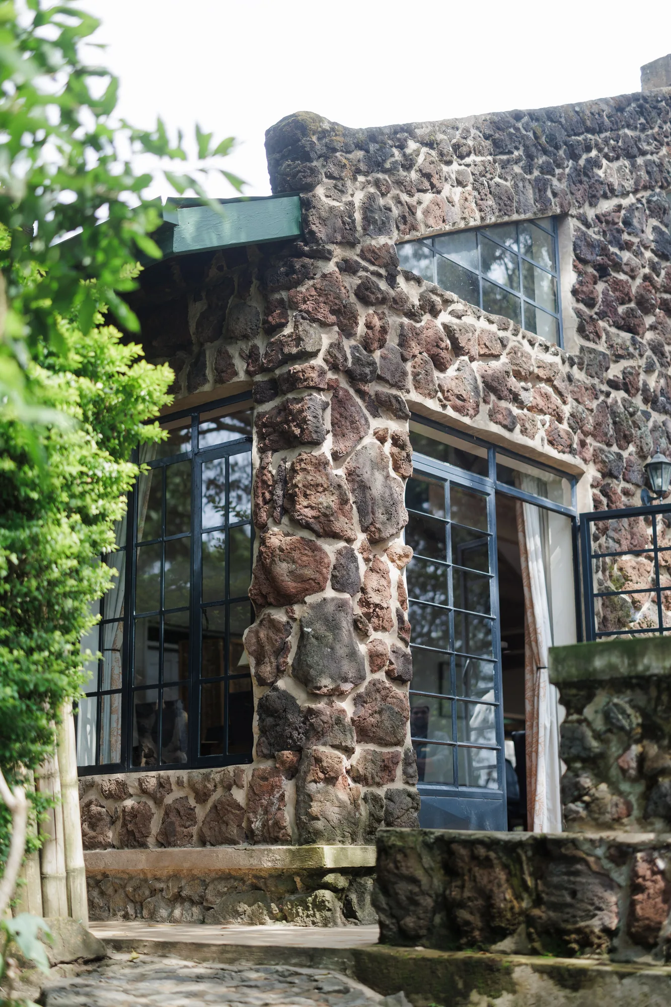 A stone cottage rises against the forest at a Nkuringo lodge