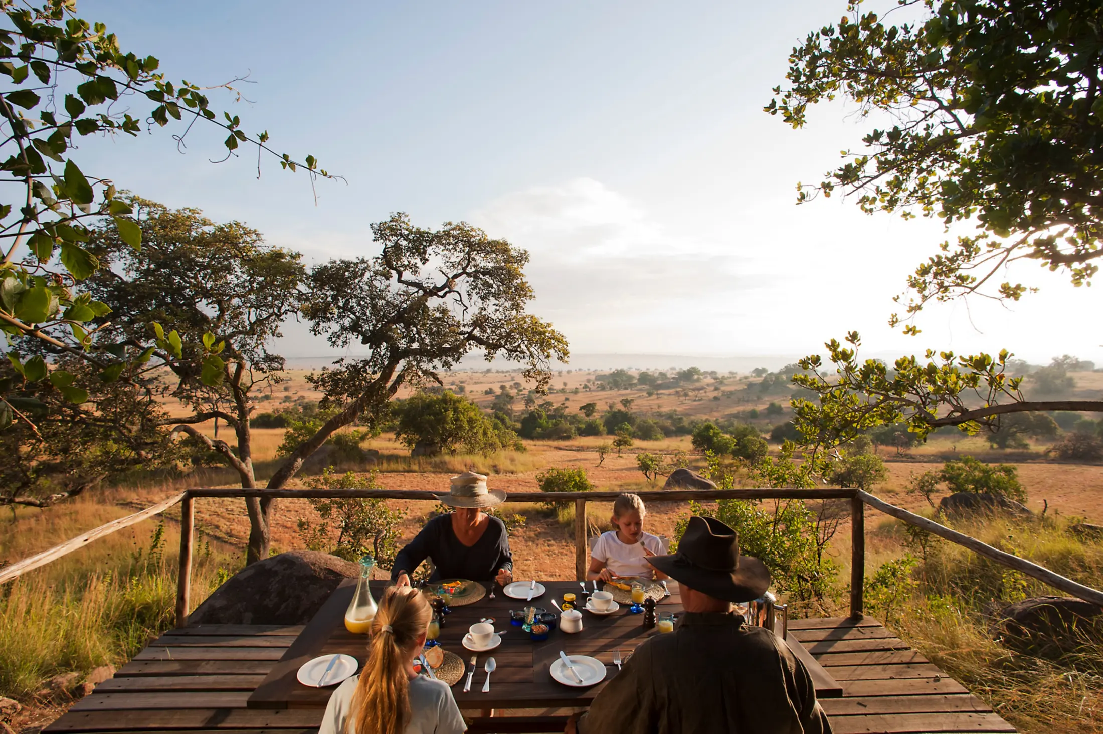 Family sharing breakfast on a deck overlooking the Serengeti