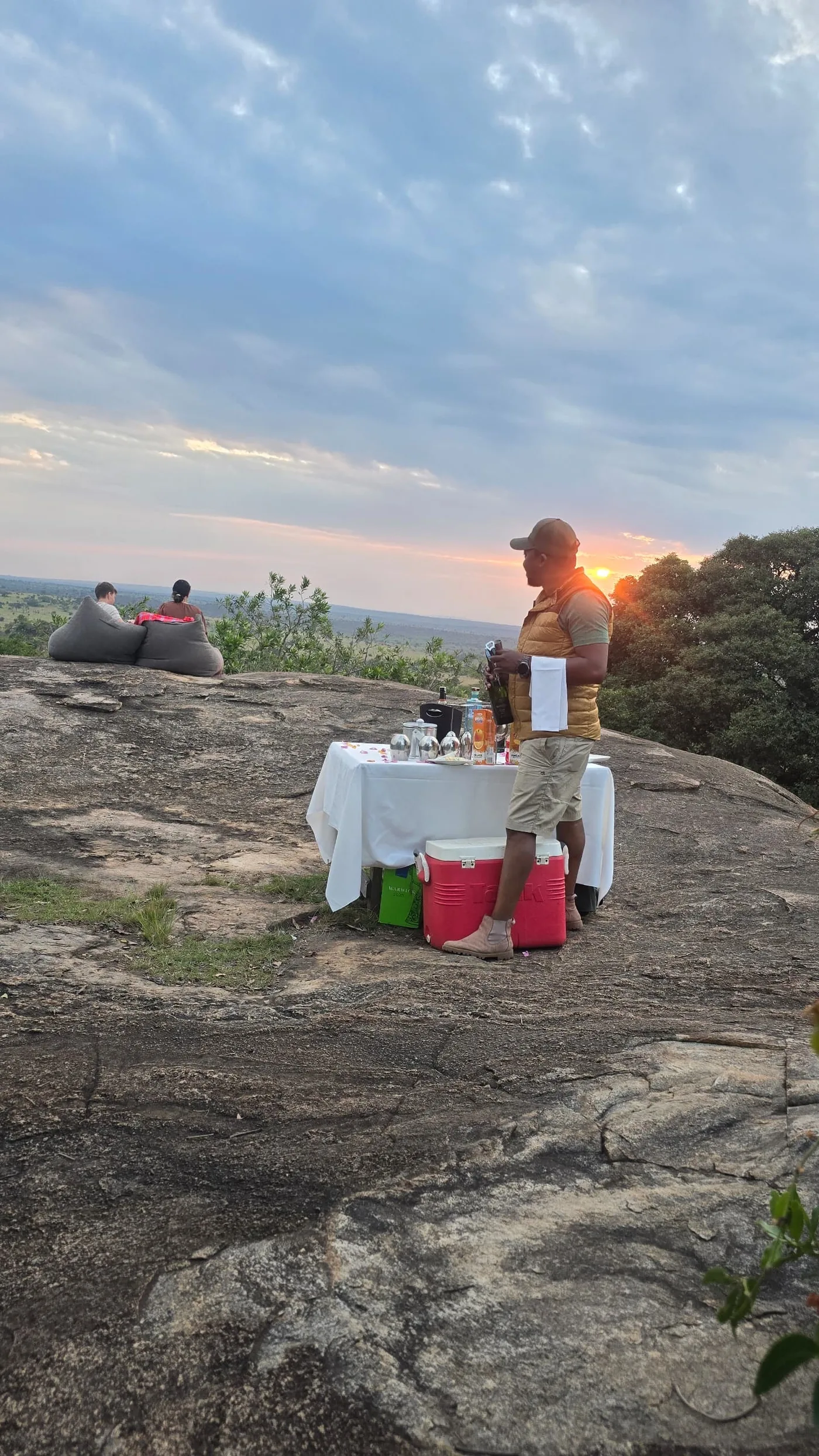 A sundowner table stands ready on a rocky outcrop at dusk