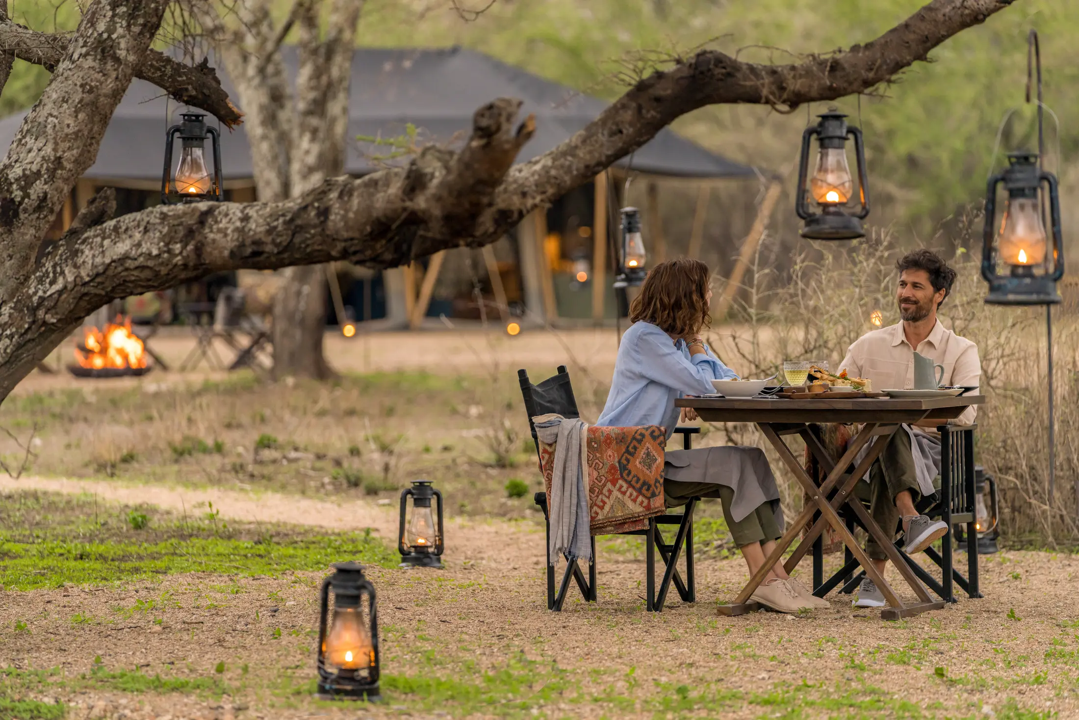 Honeymoon couple dining by lantern light at a private Serengeti camp