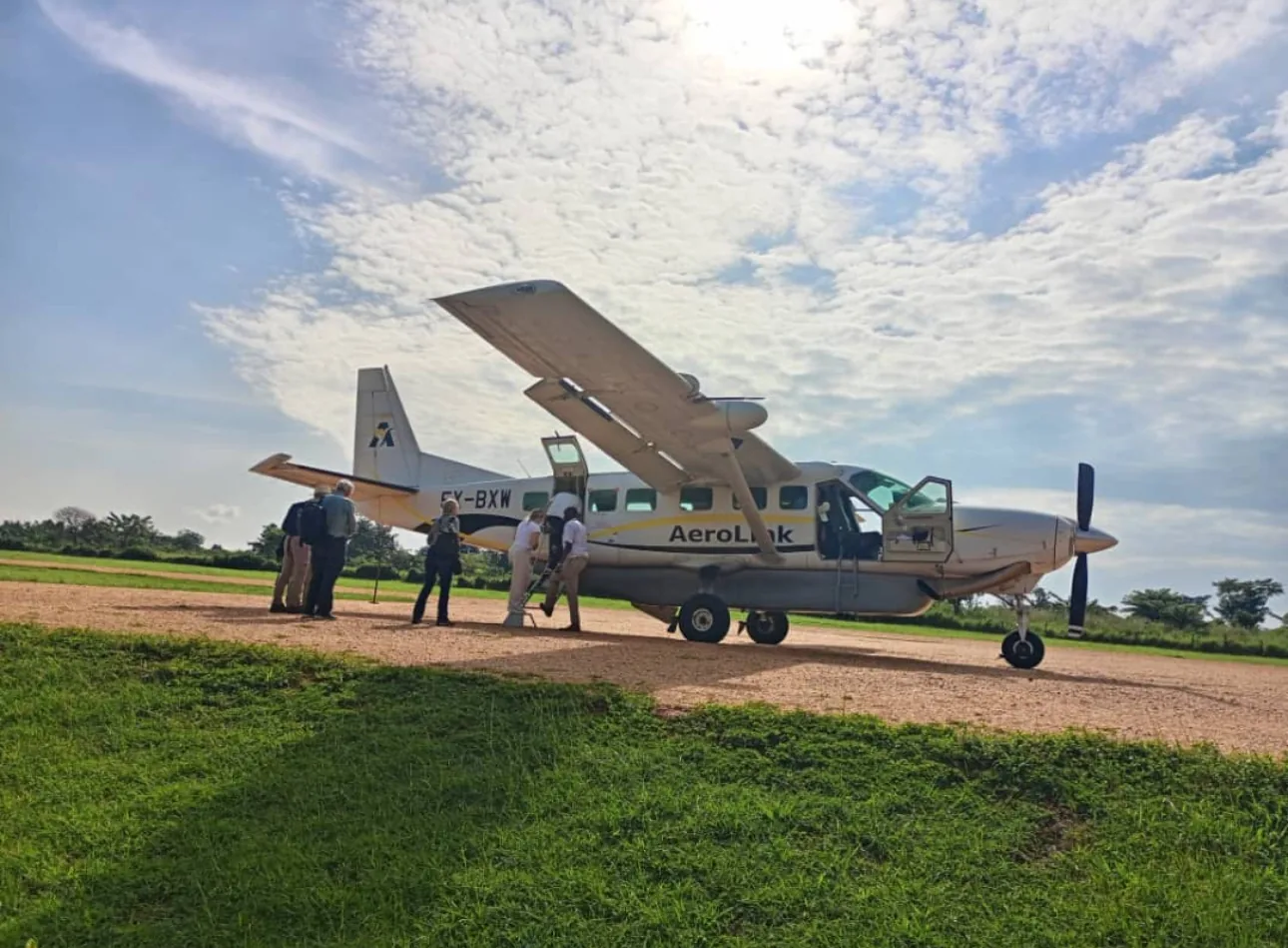 A light aircraft waits on a green Ugandan airstrip