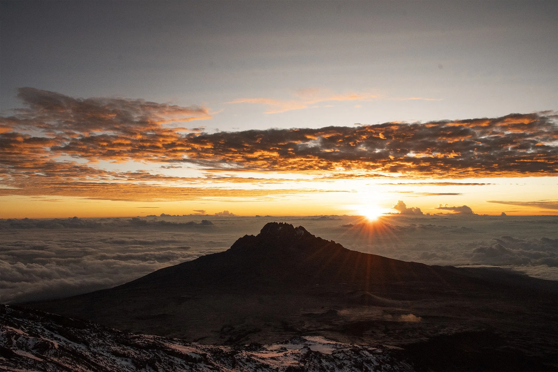 Dawn breaks over the clouds from high on Kilimanjaro