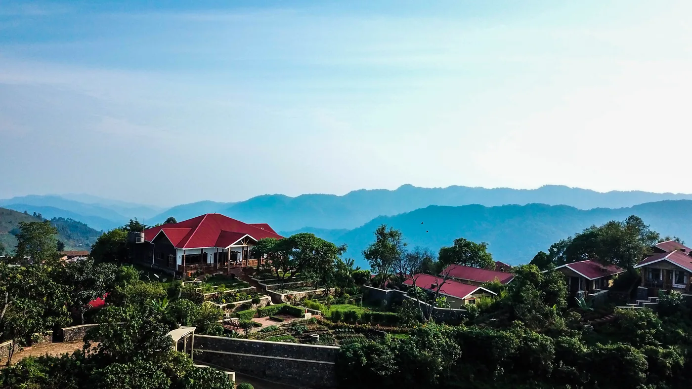 A lodge sits on the Nkuringo ridge above blue ranges of hills