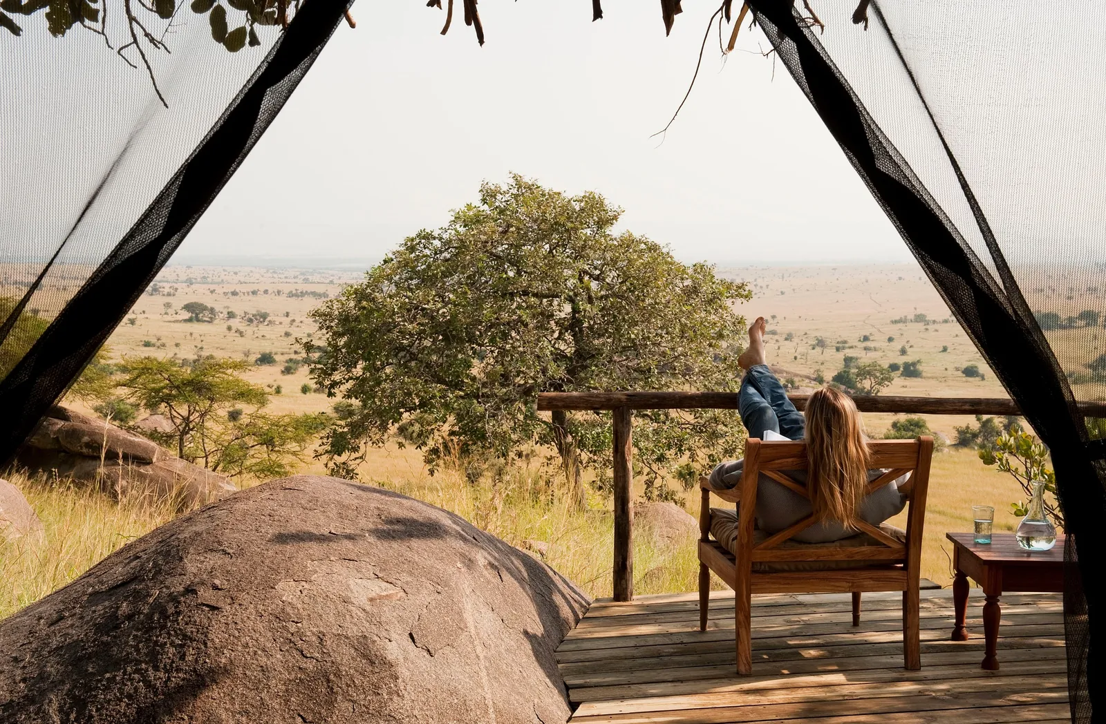 A guest looks out from a tent deck over the open plain