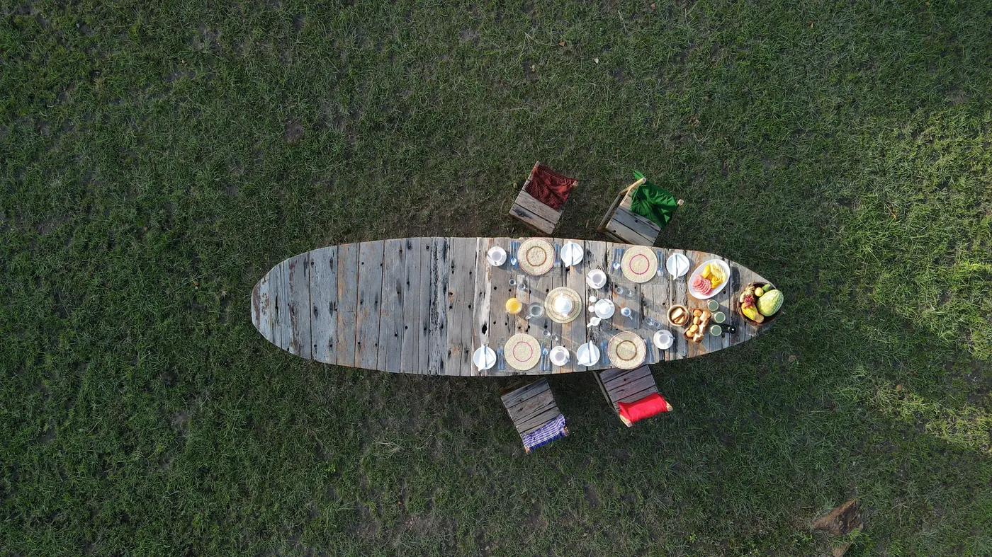 A long table stands laid on the open grass from above