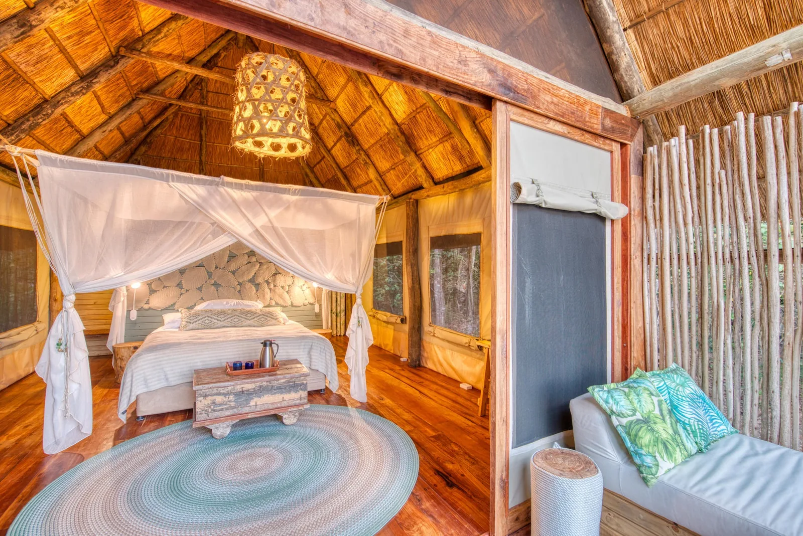 White nets drape a thatched banda bedroom near the lakeshore