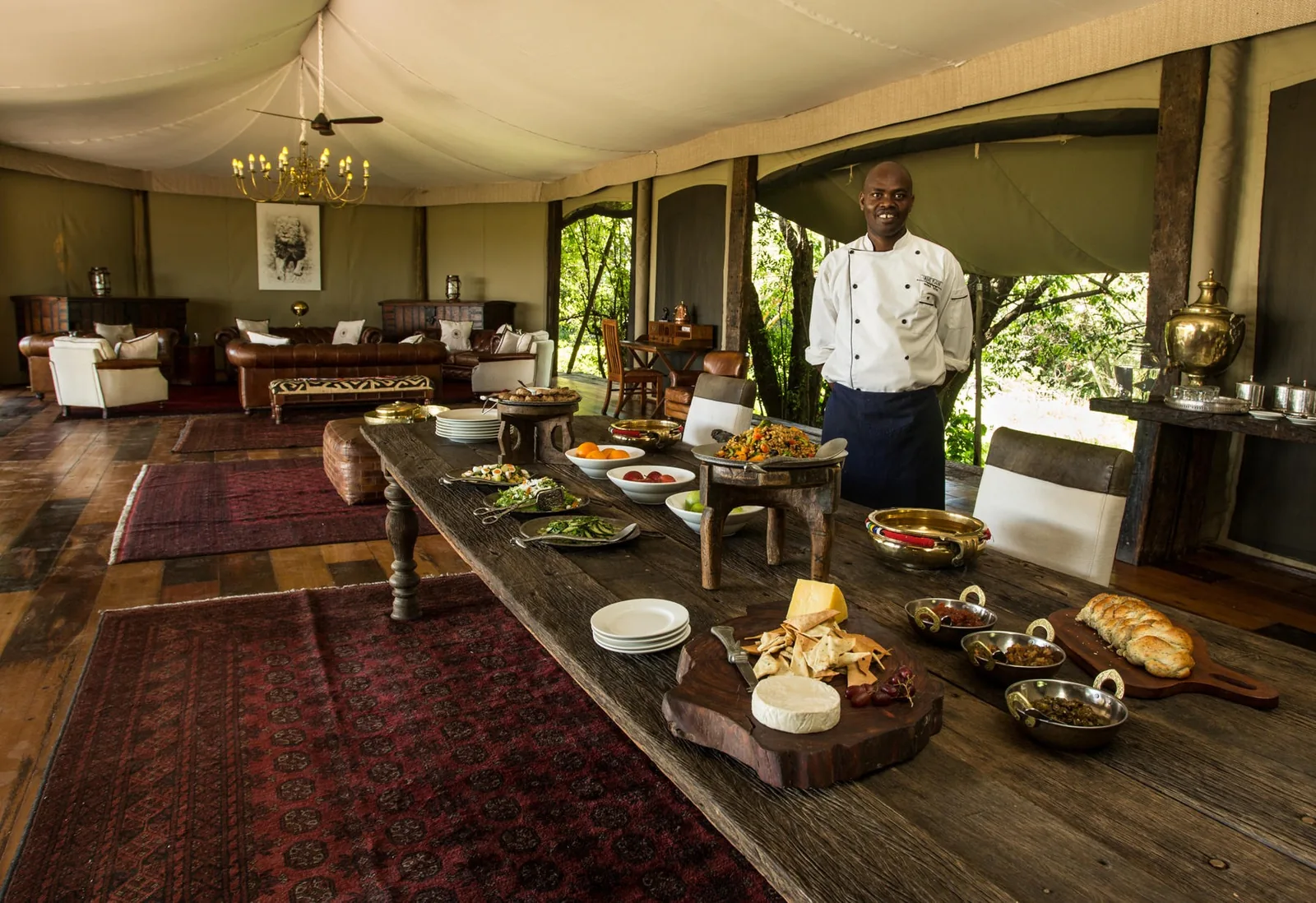 A chef presents the lunch table in a lamplit tented dining room