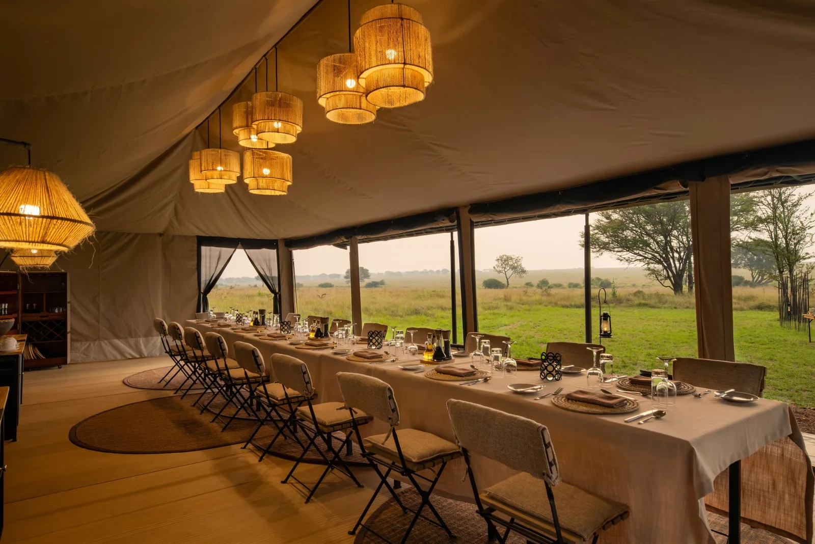 A camp dinner table glows under canvas at night