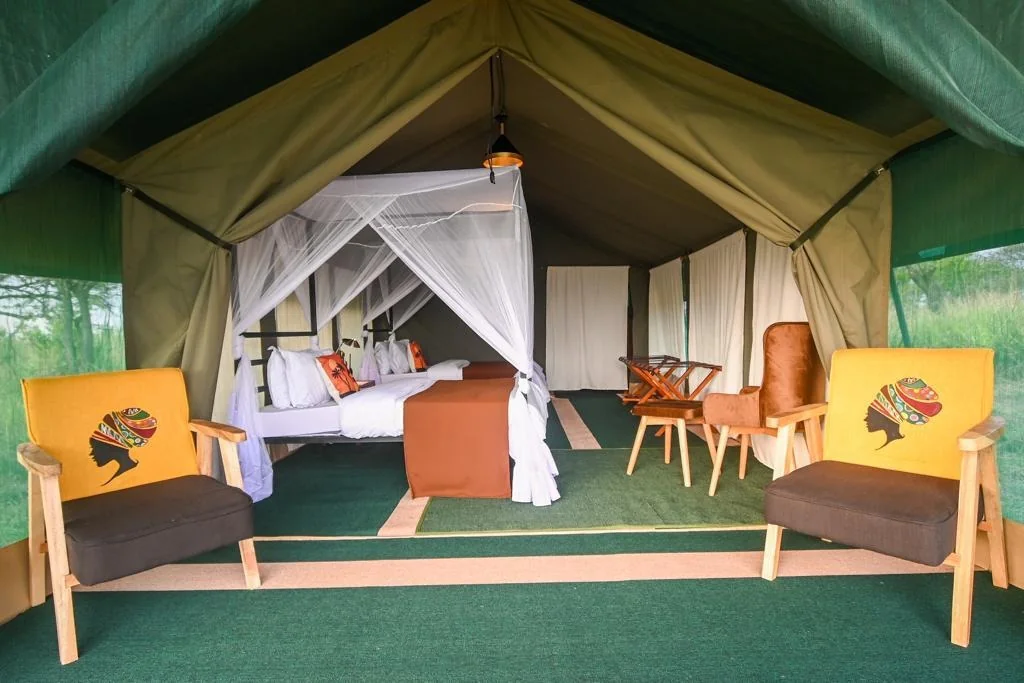 Inside a mobile camp guest tent: full bed, chairs and standing headroom