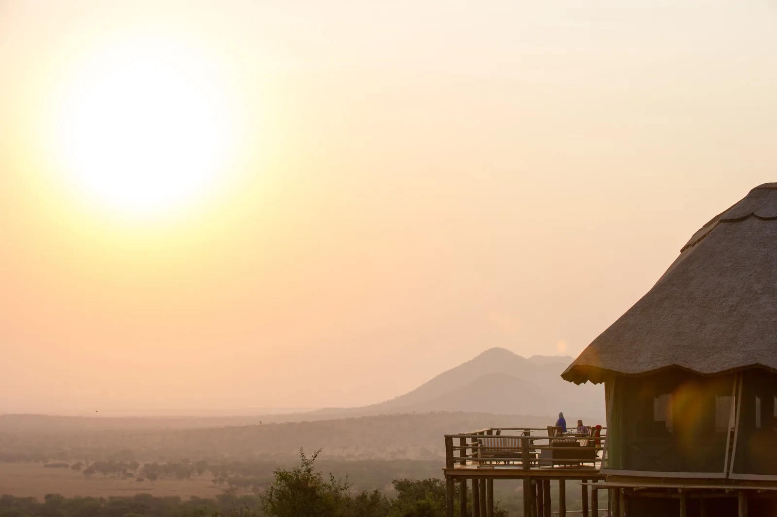 Dawn haze softens the Serengeti beyond a lodge deck