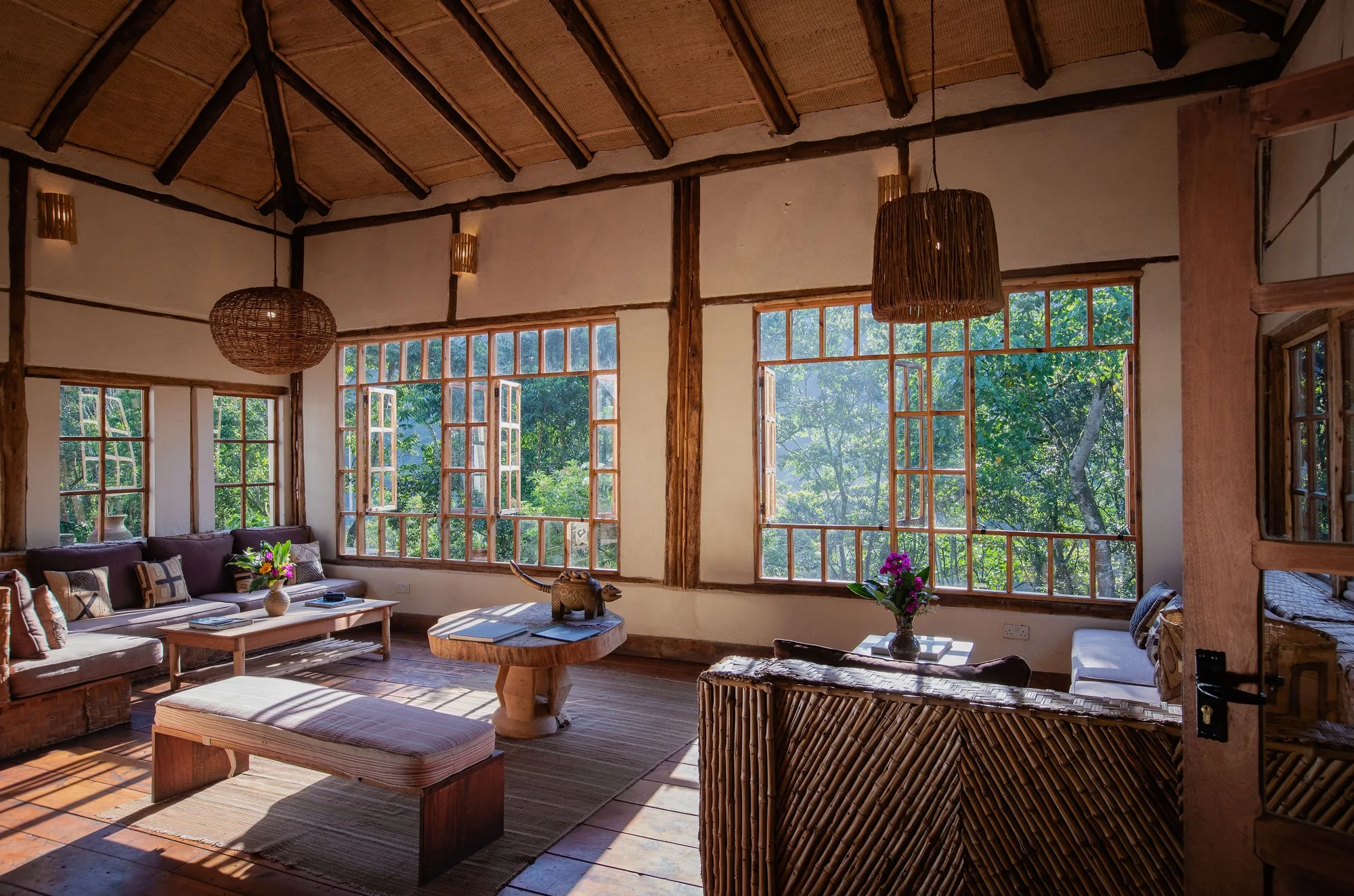 A lodge lounge opens through tall windows to the forest