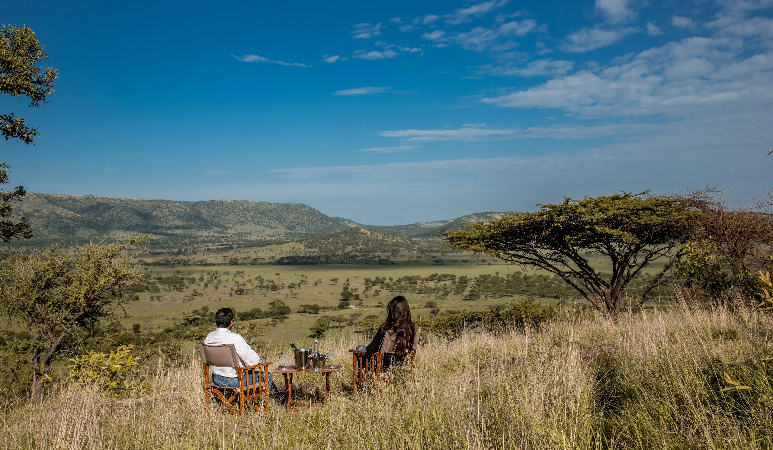 Guests and their guide share a sundowner on an open ridge