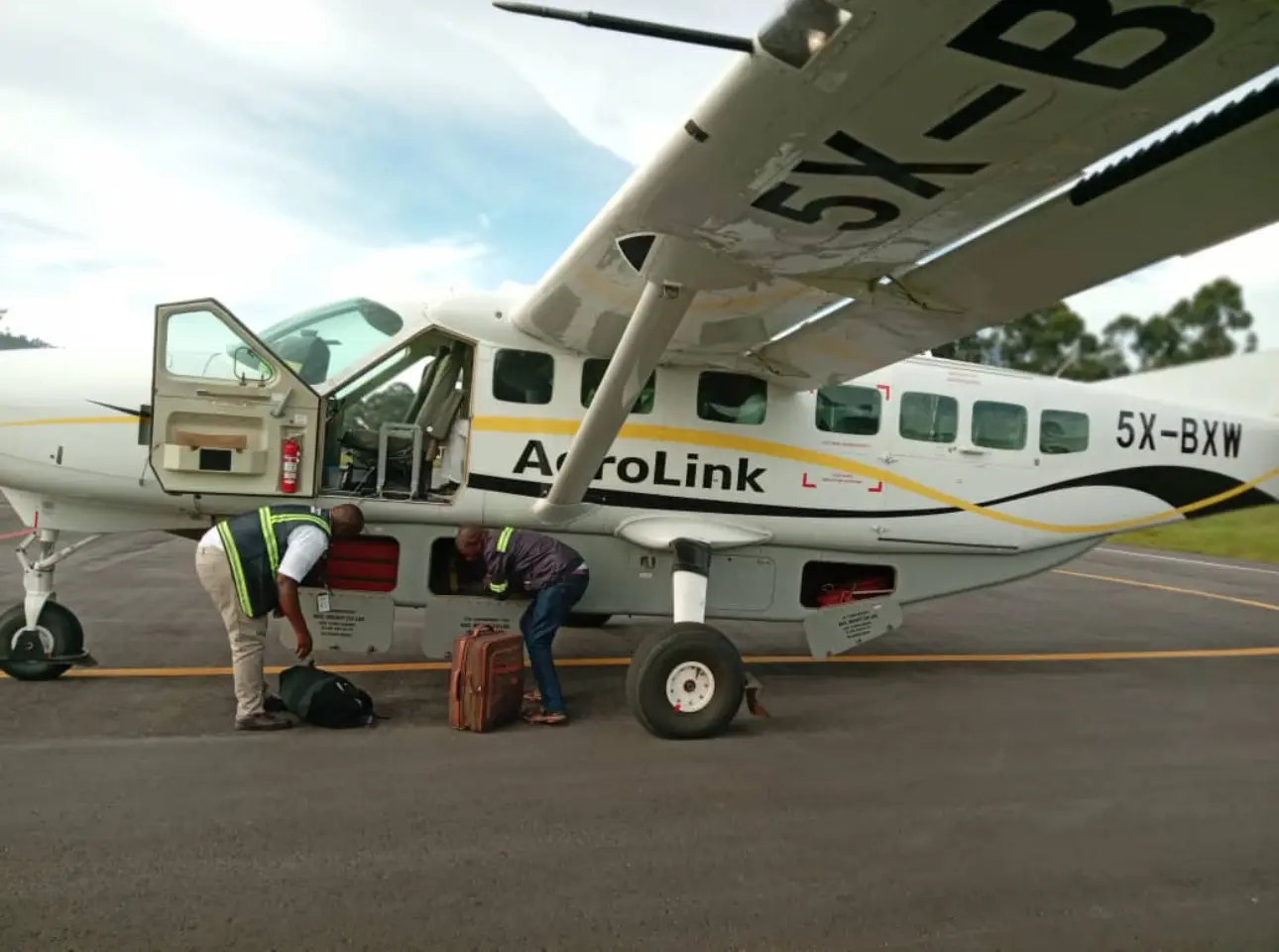 Soft-sided luggage being loaded into a small Aerolink aircraft in Uganda