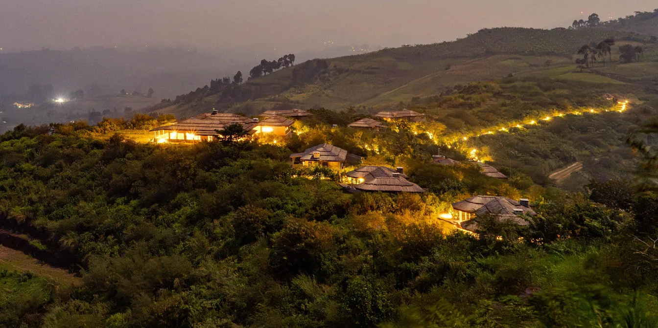 A hillside forest lodge glows at dusk near Kibale
