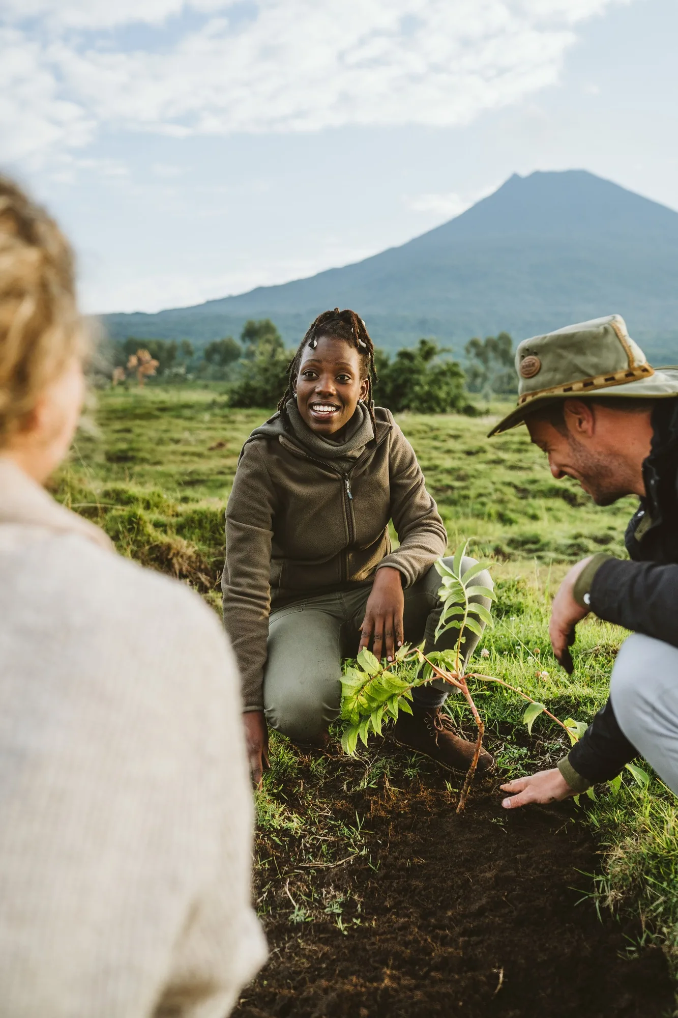 Children and guides plant seedlings beneath a volcano
