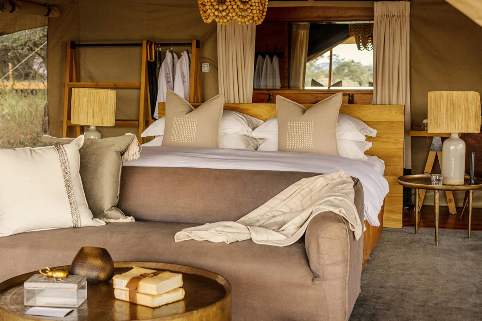 A tented suite's bed sits in soft light under high canvas