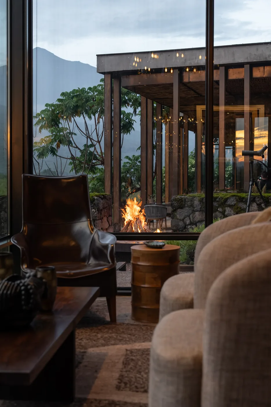 An outdoor fire burns beside a lodge lounge at dusk