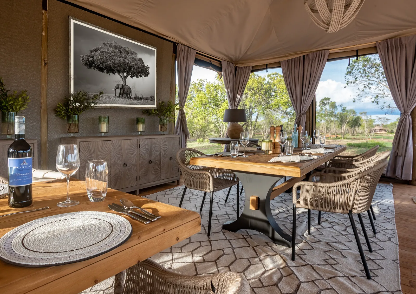 A camp dining table stands set beneath canvas