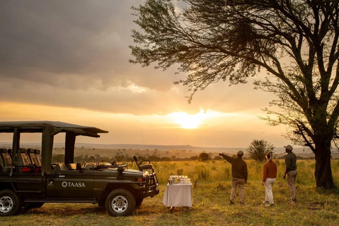 A sundowner table stands beside the camp vehicle as the light drops