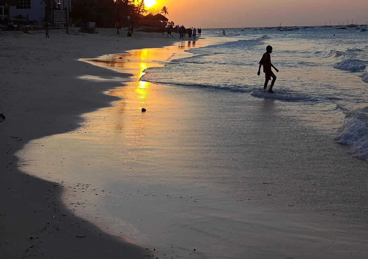A child plays in the surf at sunset on a Zanzibar beach