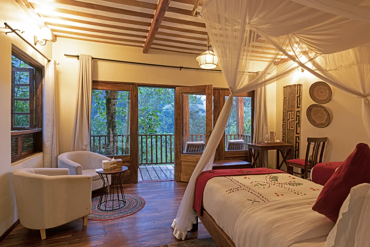 A bedroom with a draped bed and doors onto the veranda