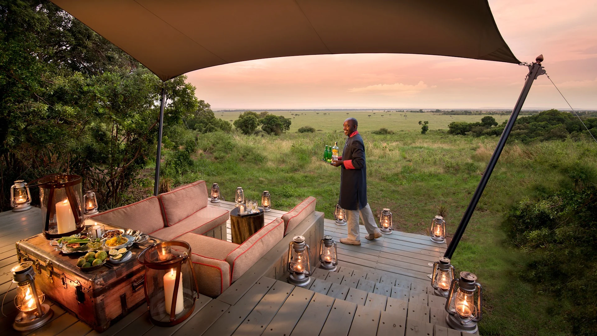 A tent deck with a sofa and lanterns, looking out over the plains