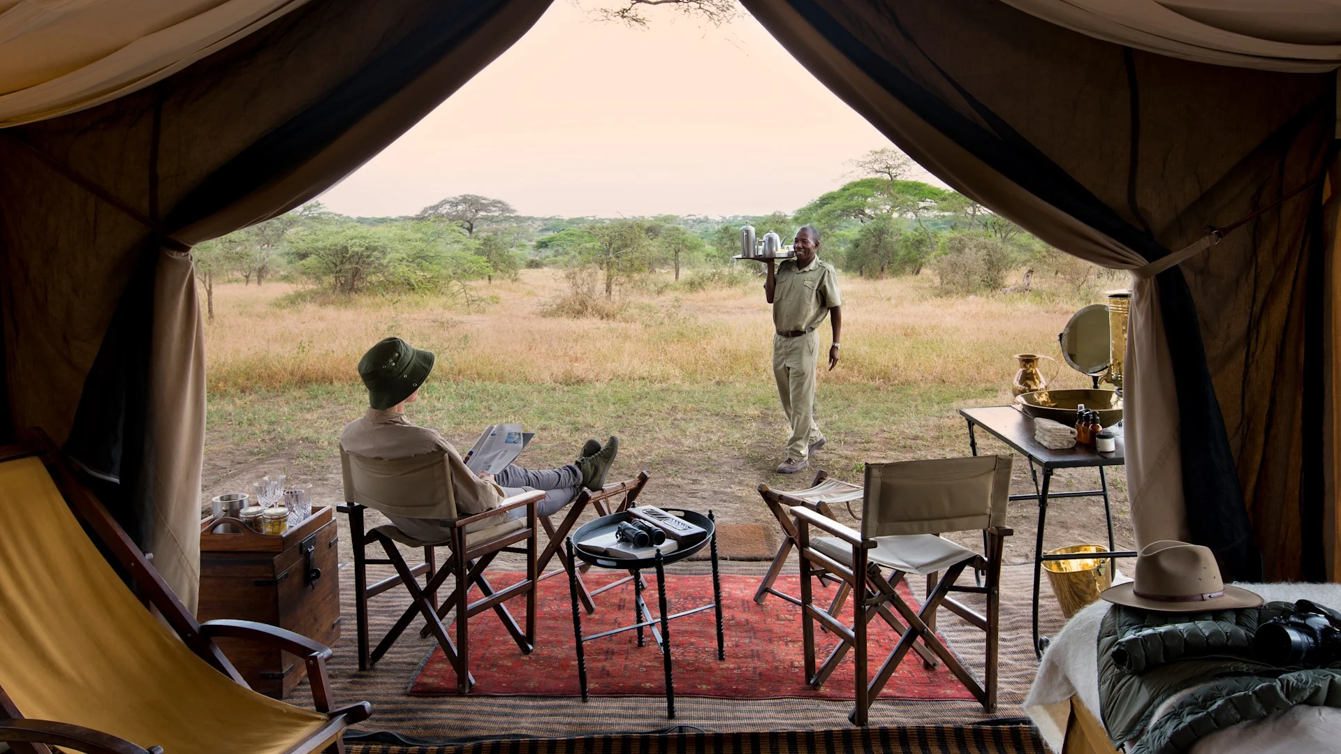 Looking out from a tent to the plains, with chairs and a table on the deck