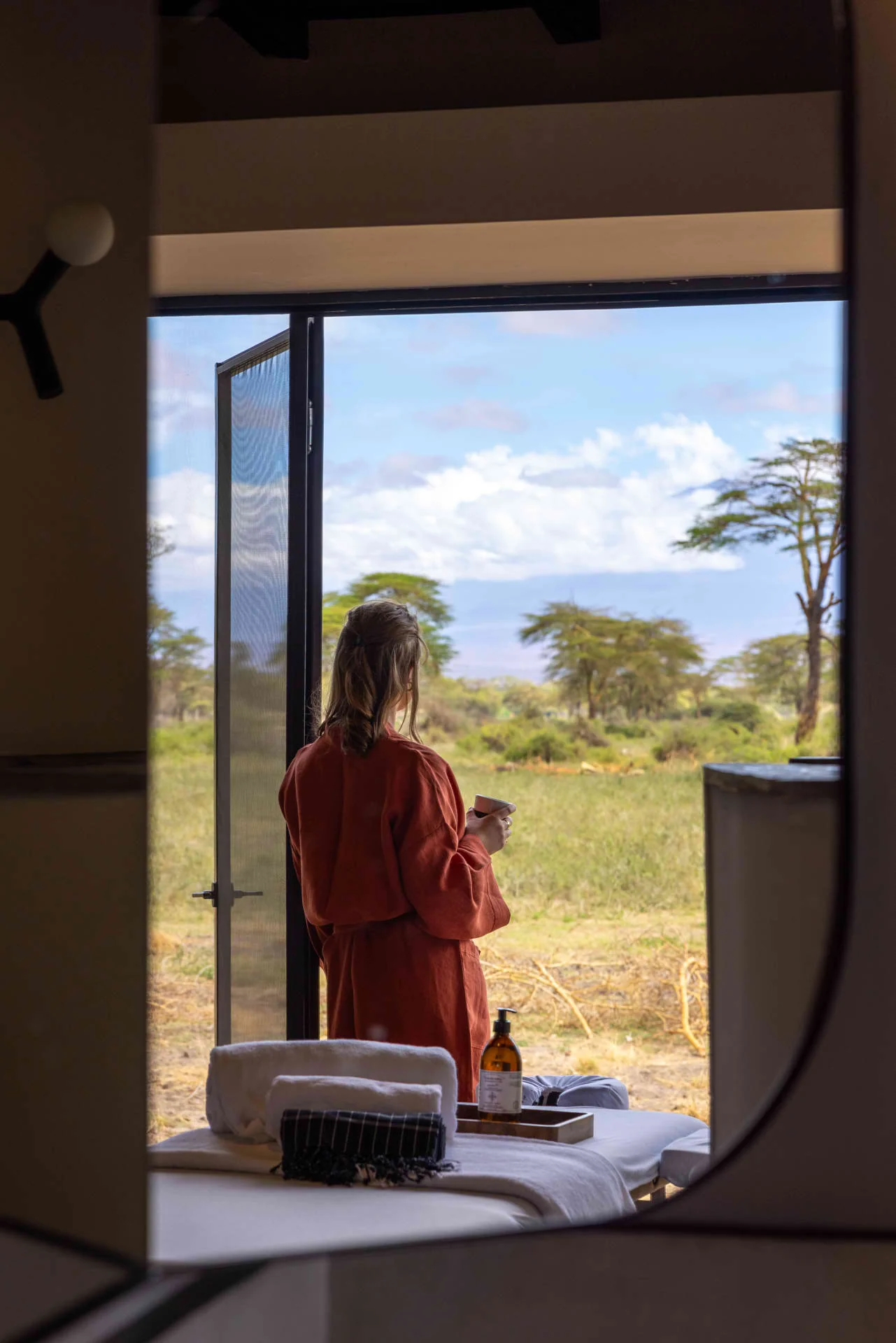 A guest at a bedroom window looking out to the plains