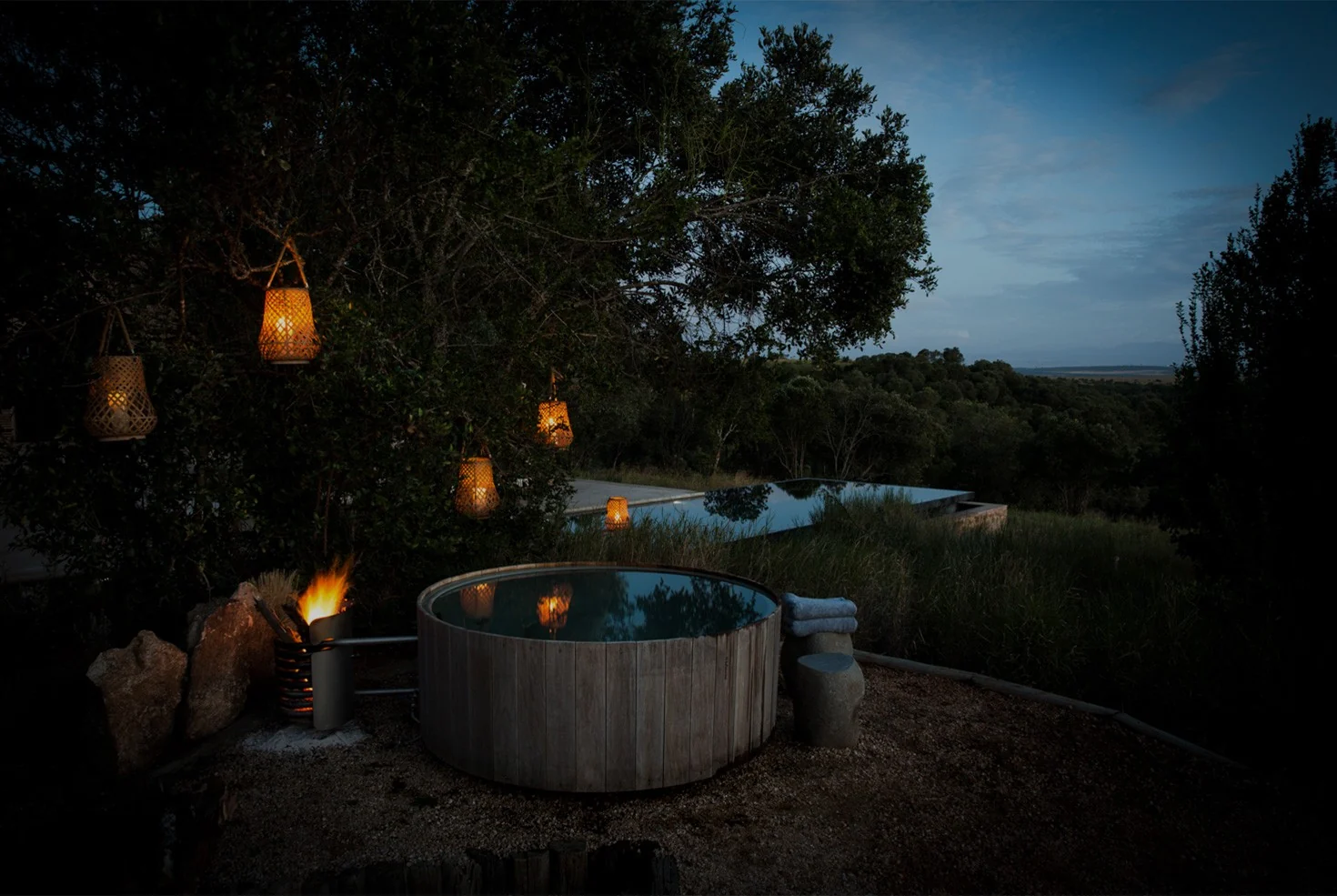 A hot tub at dusk with lanterns in the tree