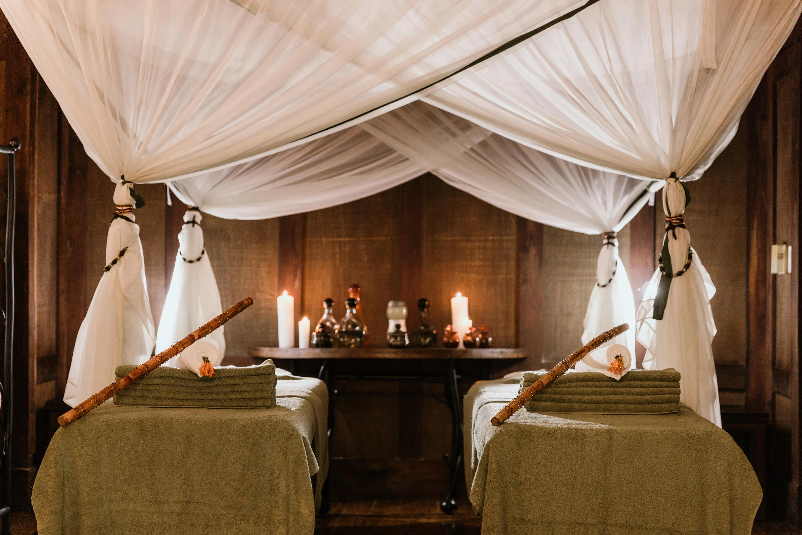 A bedroom with a draped four-poster bed and candles