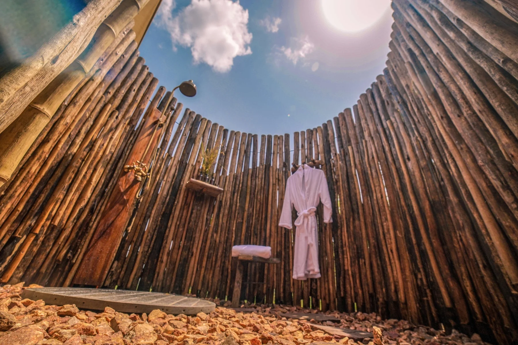 An open-air shower enclosed by a circle of timber poles